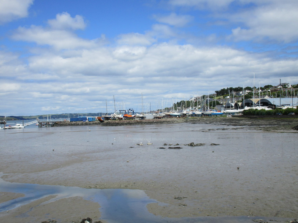 Yachts and boats at Crosshaven boatyard in Cork Harbour beneath blue sky and white clouds.